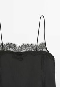 Camisole noire sans manches avec fines bretelles et bordure en dentelle fleurie sur le haut.