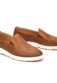 Zapatos marrones de tira perforada con una suela de goma blanca. Presentan una textura suave y puntas redondeadas para mayor comodidad y transpirabilidad.
