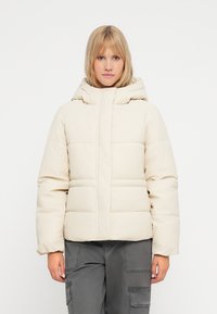 Puffjakke i lys beige med quiltet design, høj krave og hætte. Materialet ser glat og let blankt ud.