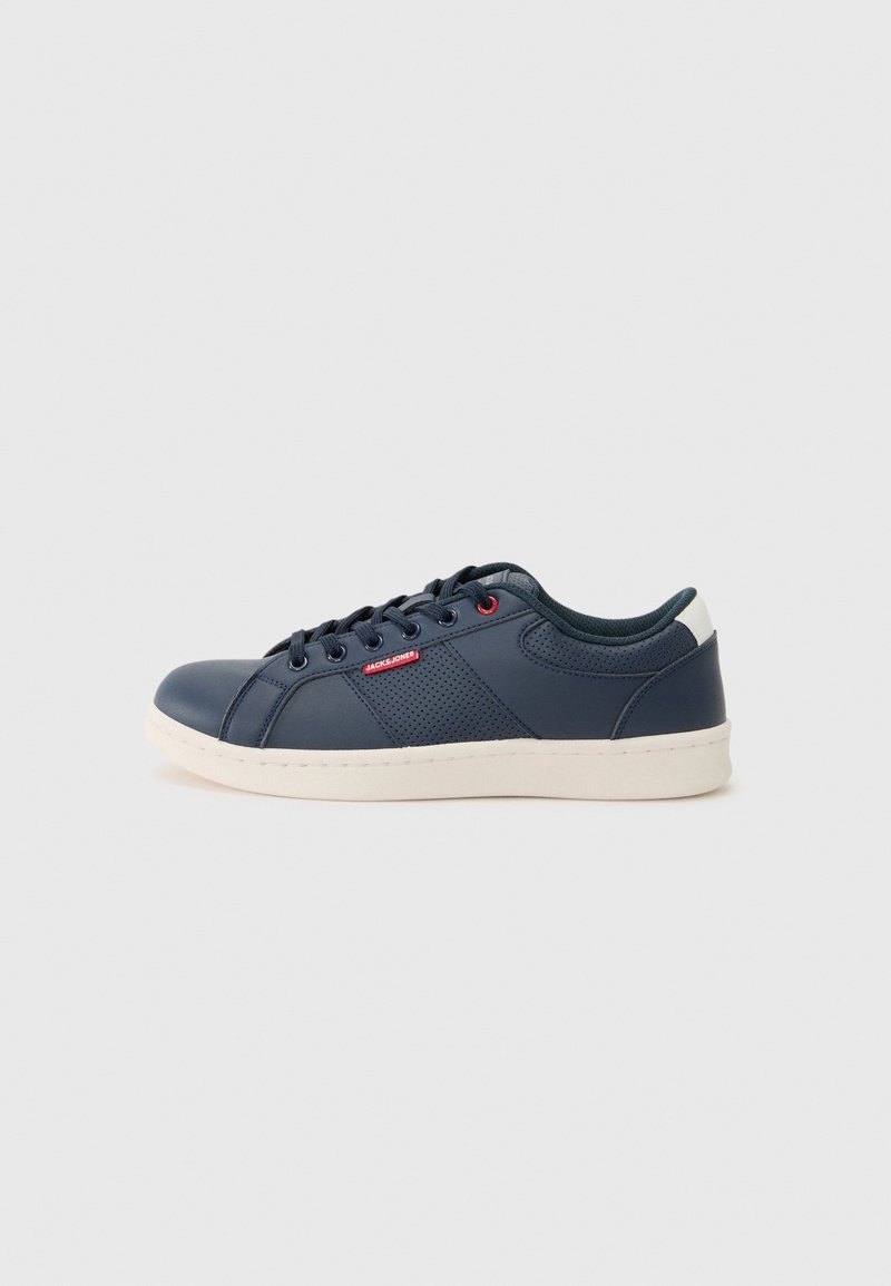 Basket basse bleu marine avec semelle blanche, laçage à l’avant, panneau latéral perforé et étiquette rouge « Jack & Jones » sur fond neutre.