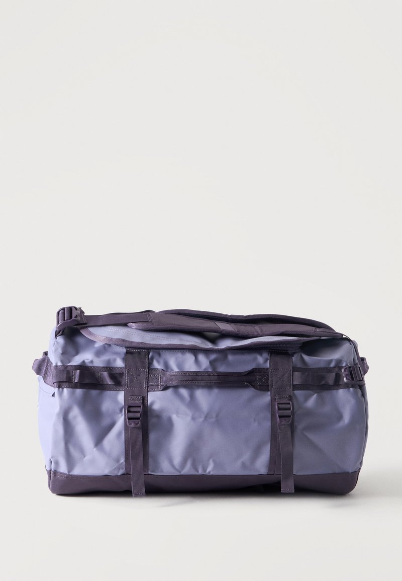 Μεγάλη μωβ τσάντα duffel με πλαϊνούς ιμάντες και χερούλια, τοποθετημένη σε απλό ανοιχτόχρωμο φόντο. Χωρίς ορατά λογότυπα ή άλλα αντικείμενα.