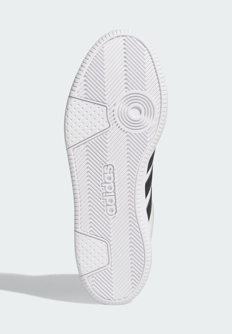 Semelle de chaussure en caoutchouc blanc avec des motifs de texture pour une meilleure adhérence, présentant un détail circulaire prominent et le logo 'adidas' en noir.