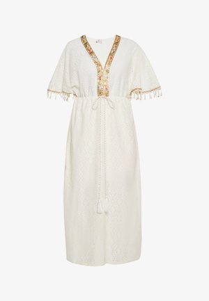 Bela obleka z V-izrezom in širokimi rokavi, ki ima cvetlične in zlate okraske ob izrezu ter resicami na koncih rokavov.