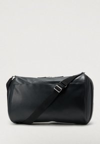 Czarna torba typu duffel wykonana z gładkiej skóry, o przestronnym wnętrzu, regulowanym pasku i srebrnych okuciach. Z górnym zamkiem na suwak.