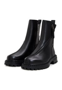 Botas de tobillo de cuero negro con cierre de cremallera, suelas gruesas tipo lug y detalles cosidos a lo largo de los bordes. Textura suave y diseño minimalista.