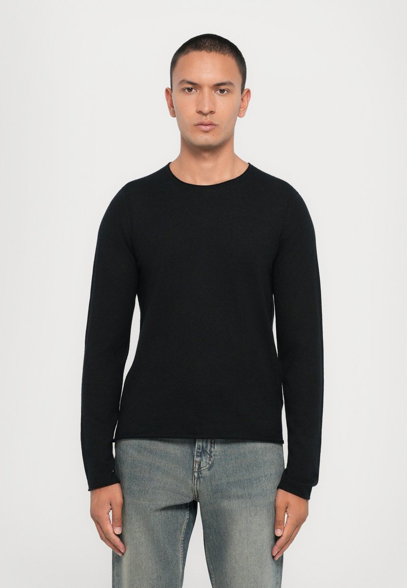 Black long-sleeve knit sweater with a round neckline, featuring a smooth texture and fitted design, paired with light blue denim jeans.