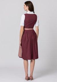 Bordeaux-rotes Kleid mit weißen Punkten, tailliertem Oberteil und fließendem Rock. Verfügt über einen kragen mit Spitzenbesatz und einen Taillengürtel in einer kontrastierenden Farbe.
