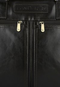 Czarna skórzana torba z dwoma złotymi suwakami, kontrastowym przeszyciem i teksturowanym wykończeniem. Wygrawerowana etykieta marki na górze.