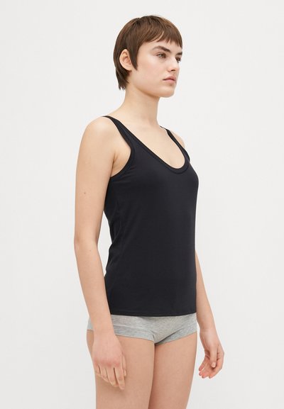 Black tank top with a deep scoop neckline and narrow straps, paired with gray shorts. Smooth fabric and fitted design. Simple, minimal style.