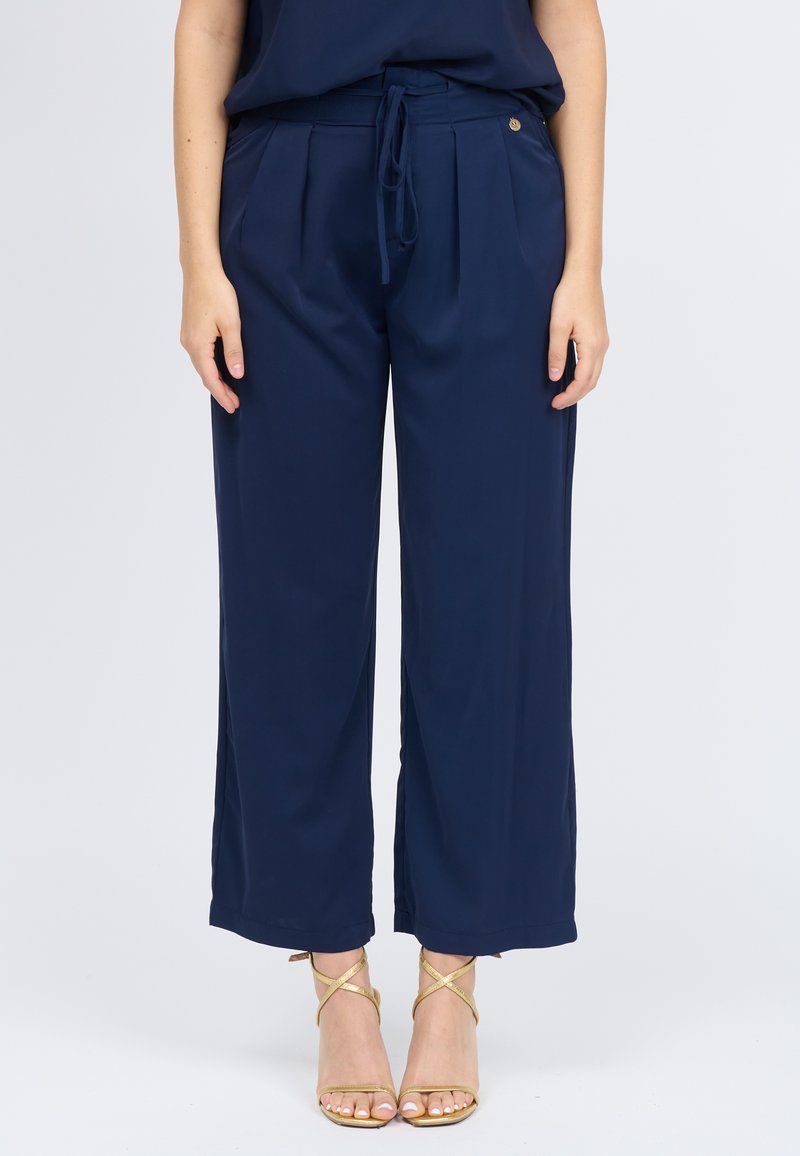 Marineblauwe wijde broek gemaakt van lichtgewicht stof met een hoge taille, plooien en een strikceintuur. Afgewerkt met subtiele gouden accenten.