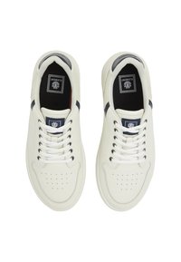 White leather sneakers featuring six eyelets, navy accents on the heel, and perforated texture on the toe. Black inner lining.
