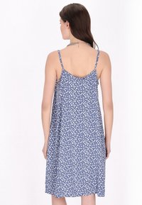 Rochie albastră cu model floral alb, dintr-un material ușor, cu bretele subțiri și o siluetă A-line lejeră. Vederea din spate arată pliurile și gâtul.