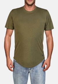 T-shirt verde oliva, maniche corte, scollo rotondo, materiale in cotone morbido, orlo curvo sul fondo, etichetta sul lato sinistro.