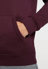 Sudadera burdeos con mangas largas, bolsillo tipo canguro, puños y dobladillo acanalados, hecha de una suave mezcla de algodón.