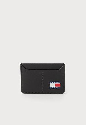 Zwart leren kaarthouder met een gladde textuur, voorzien van een logo-patch in blauw, rood en wit. Slim design met een afgeschuind rand.