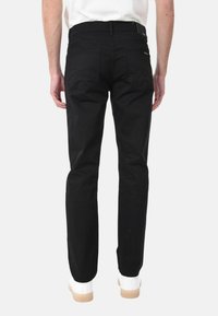 Pantaloni in twill di cotone neri con design a gamba dritta, tasche posteriori e vita. Presentano cuciture bianche e un'etichetta del marchio discreta.