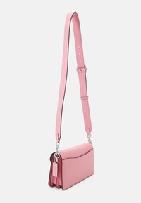 Sac à bandoulière en cuir rose avec une texture lisse, des coins arrondis et une bandoulière amovible. Il présente des ferrures argentées et un détail en forme d'étiquette.