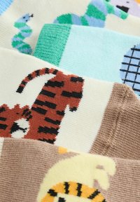 Nahaufnahme eines gestrickten Stoffes mit Tiger- und Schlangenmotiven in Braun-, Grün- und Blautönen auf weichem Material.