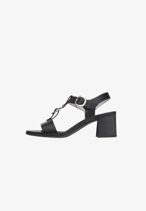 Sandali con tacco in pelle nera con design a T-bar, cinturino regolabile alla caviglia e tacco a blocco quadrato. Presentano dettagli in metallo argentato.