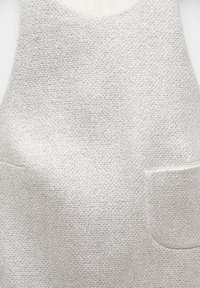 Haut sans manches gris clair texturé avec encolure arrondie et deux poches plaquées à l'avant.