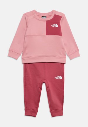 To-delt toddler sæt med langærmet lyserød og rød sweatshirt og matchende røde bukser, begge med The North Face logo.