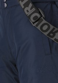 Marineblå bukser lavet af slidstærkt materiale med en frontlomme og et broderet "North Bend"-logo. Inkluderer en bred sort rem med grå tekst.