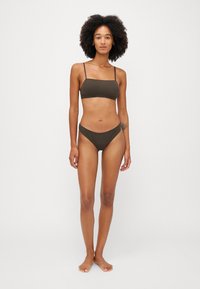 Dyp sjokoladebrun bikini-sett som har en bandeau topp med tynne stropper og lave bunn. Glatt tekstur, minimalistisk design.