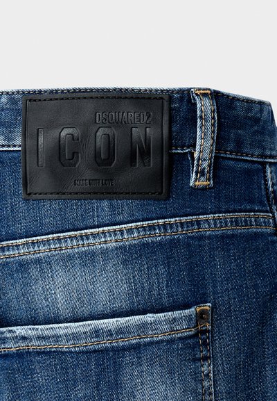 Tummansiniset farkut, joissa on teksturoitu musta nahkainen logopatchi, jossa lukee "DSQUARED2 ICON" vyötäröllä ja näkyvät ompelutiedot.