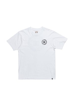 T-shirt en coton blanc avec un col rond, des manches courtes et un logo DC noir circulaire sur la poitrine gauche. Texture lisse, coupe classique.