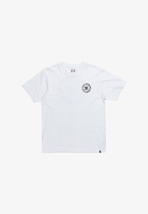 T-shirt en coton blanc avec un col rond, des manches courtes et un logo DC noir circulaire sur la poitrine gauche. Texture lisse, coupe classique.