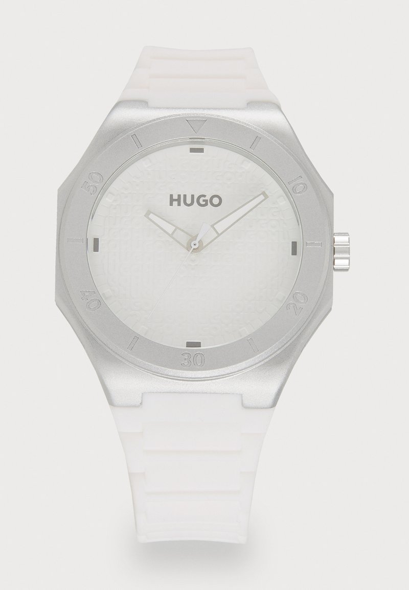 Relógio com bracelete de silicone branco e bezel em aço inoxidável prateado. Mostrador branco texturizado com o logótipo "HUGO" e marcadores de horas prateados.