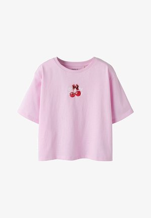 Różowy krótki t-shirt z krótkim rękawem, zdobiony grafiką dwóch czerwonych wiśni związanych kokardką oraz częściowo widocznym białym napisem.