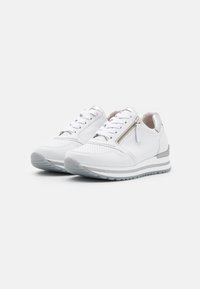 Vita sneakers med en texturerad ovandel, silverdetaljer, snörning och en sidogömma; har en vadderad sula och kontrasterande grå detaljer.