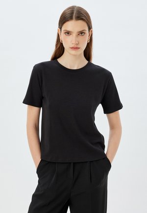 Svart T-shirt med kort ärm och rund halsringning, tillverkad av ett mjukt tyg. Designen har en avslappnad passform och minimal detaljering.