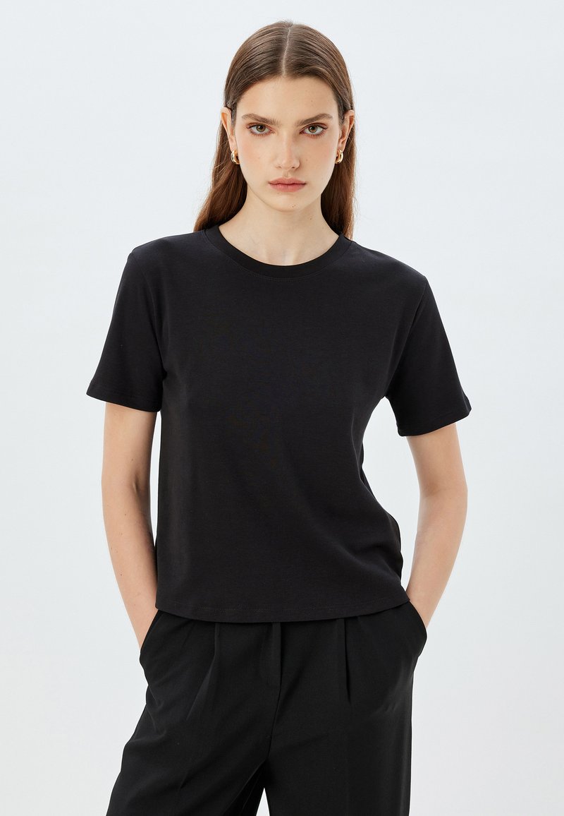 Sort kortærmet T-shirt med rund hals, lavet af et glat materiale. Designet har en afslappet pasform og minimal dekoration.