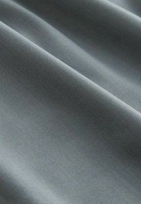 Campione di tessuto, tessuto intrecciato, tonalità grigia, texture liscia con leggera brillantezza, caratterizzato da un motivo a righe diagonali per la durabilità.