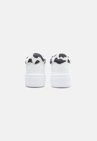 Λευκά αθλητικά παπούτσια με ανάγλυφο μοτίβο μαύρου και άσπρου γαλοτύπου στη φτέρνα, με παχύ λευκό πέλμα με ανάγλυφο το γράμμα "Valentino."