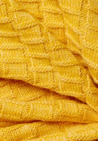 Żółta dziana tkanina charakteryzuje się teksturowanym wzorem w diamenty z subtelnymi różnicami w grubości, co tworzy przytulny i ciepły wygląd.