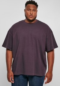 Tricou oversized din bumbac violet, cu guler rotund și mâneci scurte, asortat cu blugi din denim albastru. Textură netedă, croi lejer.