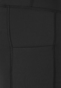 Leggings neri in tessuto elasticizzato con cuciture piatte, dotati di una tasca laterale e una texture liscia per comfort e libertà di movimento.