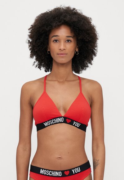 Rød trekantet bralette i blødt stof med justerbare stropper og et sort elastisk bånd med "MOSCHINO ❤️ YOU" i hvid tekst.
