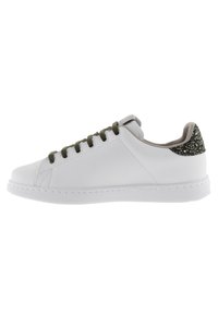 Sneaker bianca in pelle con suola in gomma piatta, lacci verdi e un accento glitterato nero sul tallone. Punta rotonda e design minimalista.