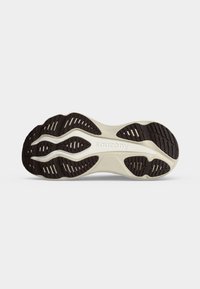 Σόλα από παπούτσι τρεξίματος Saucony με μαύρα σχέδια πέλματος και μπεζ ενδιάμεση σόλα σε λευκό φόντο.