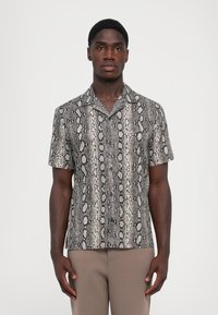 Chemise à manches courtes avec un design imprimé serpent noir et beige, fabriquée en matériau lisse. Col classique et coupe décontractée.