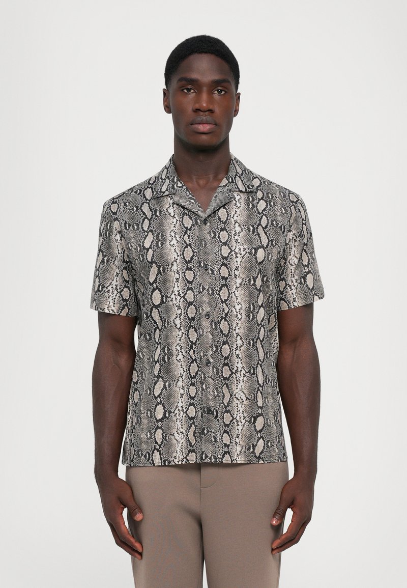Chemise à manches courtes avec un design imprimé serpent noir et beige, fabriquée en matériau lisse. Col classique et coupe décontractée.