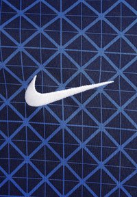 Tissu de sport bleu marine avec un motif de grille géométrique bleue et un logo Nike brodé en blanc sur le côté gauche.