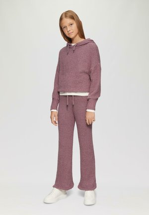 Krótkie, kapturowe sweter oraz pasujące spodnie z teksturowanej tkaniny w kolorze mauve, z elastycznym paskiem w talii i białymi akcentami przy mankietach, zestawione z białymi trampkami.