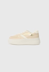 Beige plattform sneakers med hvit såle. Har metallisk gull aksenter og en jevn tekstur. Snøring med avrundet tå.