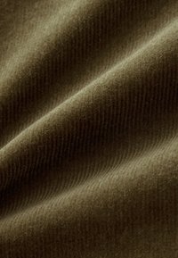 Tessuto in corduroy verde oliva con sottili righe verticali, texture morbida e un aspetto caldo e peloso, adatto per varie applicazioni tessili.