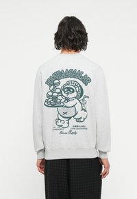 Sudadera gris de cuello redondo con un gran gráfico verde en la parte posterior de un oso sosteniendo alimentos, con texto y una fecha debajo.